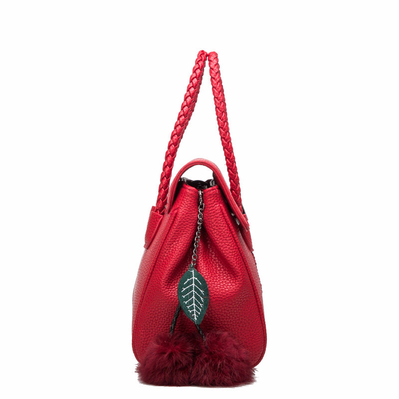 Red leather handbag side view with braided handle and cherry charm