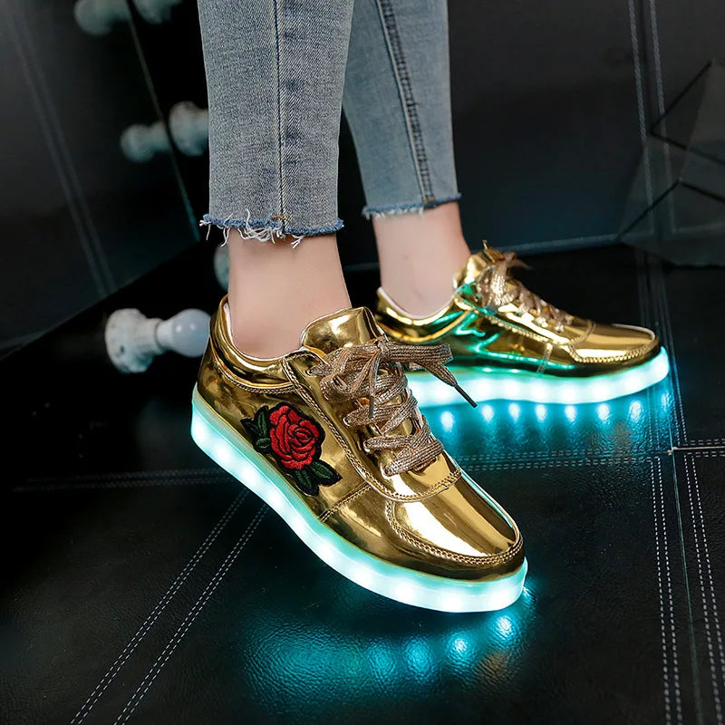 Metallic gold sneakers with red rose embroidery and LED light soles, a cushioned slip-on shoe for glowing party looks.