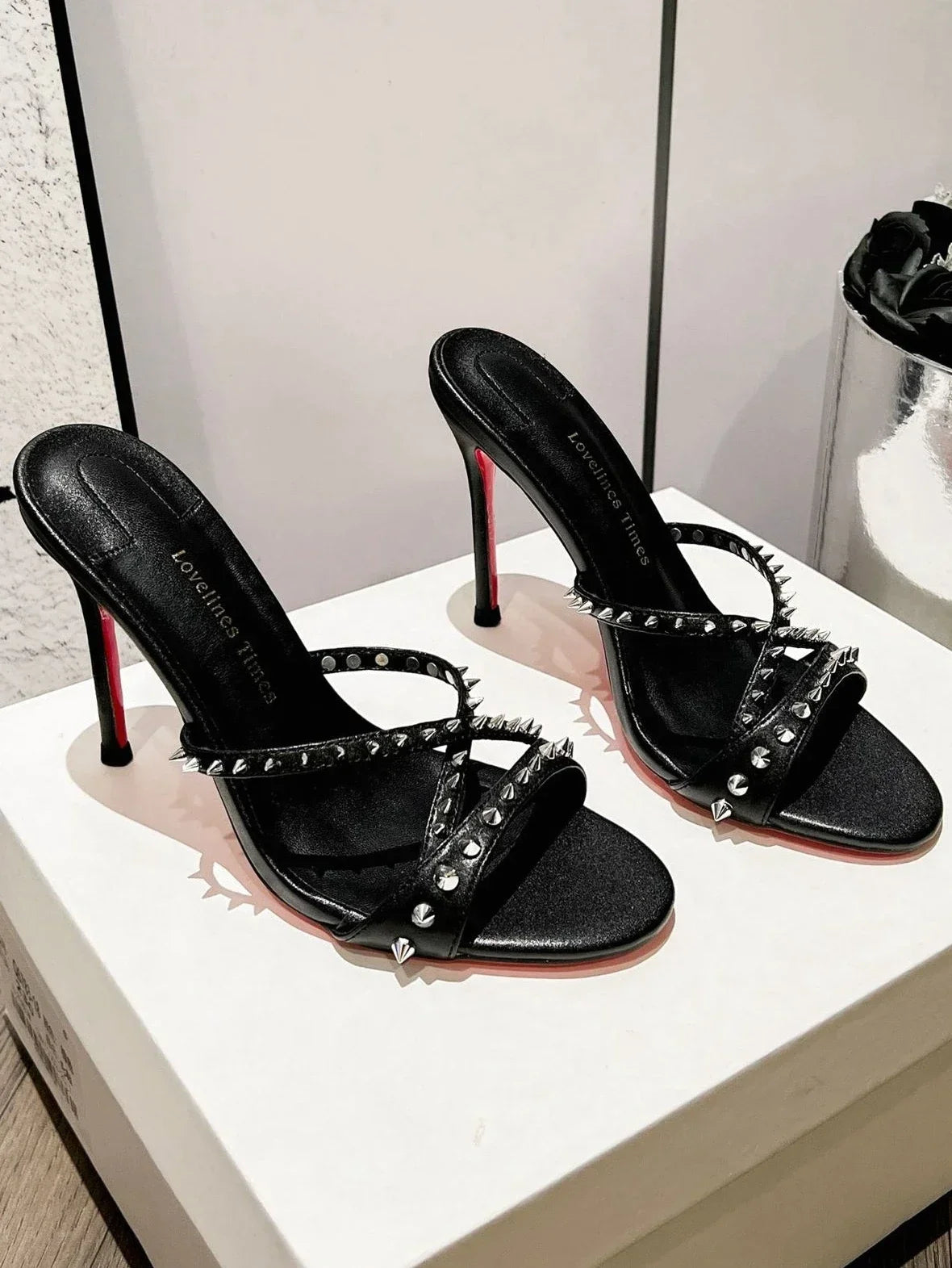 Black strappy high heel sandals with silver studs and red soles for formal evening events.