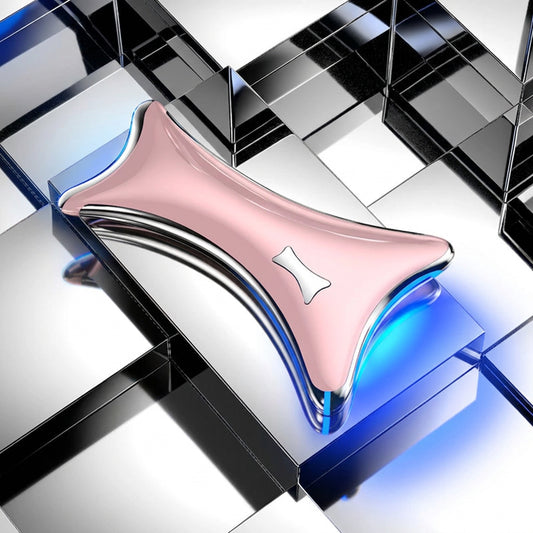 Pink and silver ergonomic facial massager device resting on a reflective geometric surface.