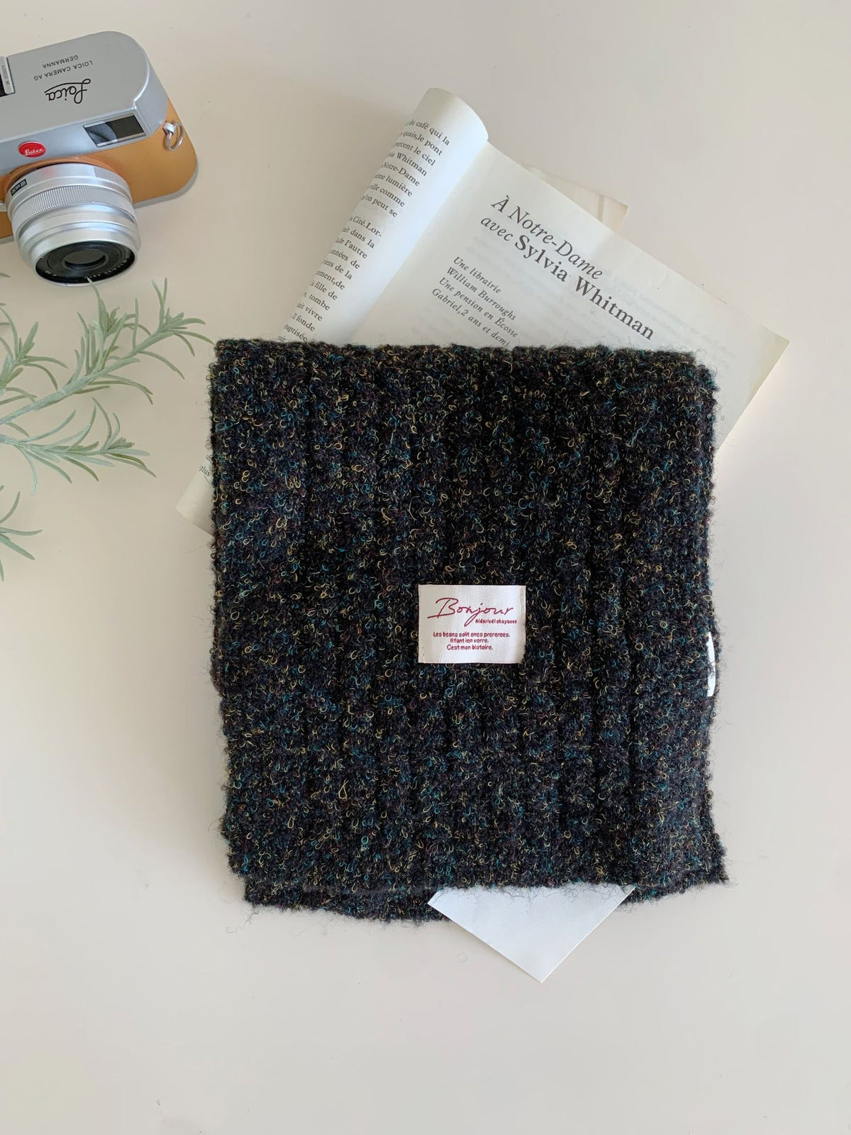 Folded dark knit scarf with a small white fabric tag on the front.