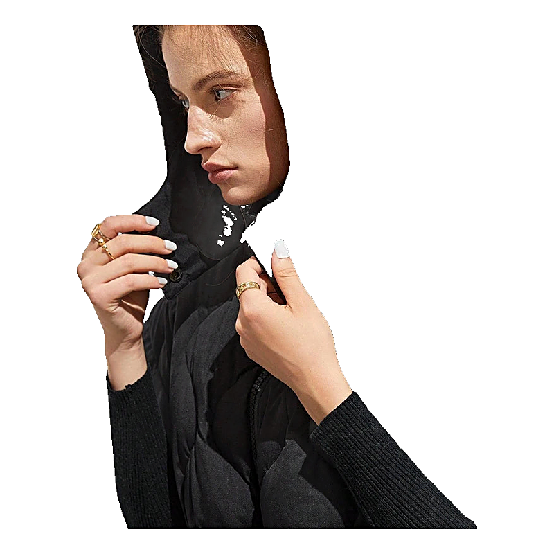 Woman wearing a black quilted puffer vest with hood and black long-sleeve underlayer.