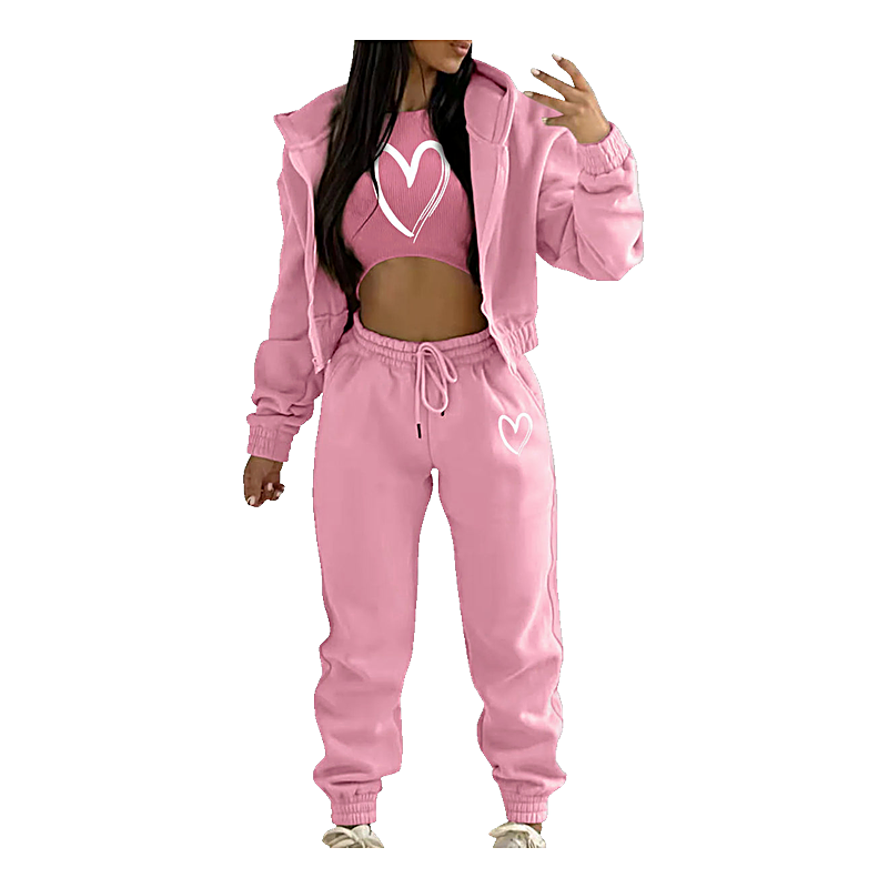 Pink three-piece jogger set with zip hoodie, crop top, and sweatpants featuring white heart graphics.