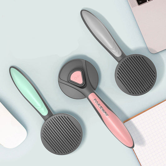 Three ergonomic pet grooming brushes in grey with mint green, pink, and grey handles.