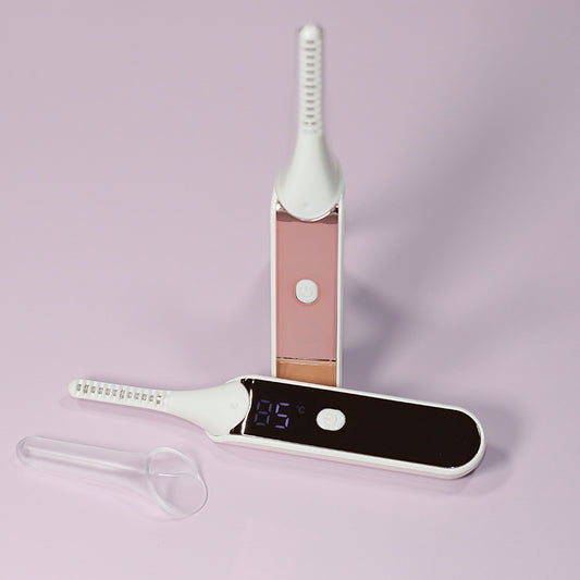 Two heated eyelash curlers in white and rose gold with digital temperature displays and a clear protective cap.