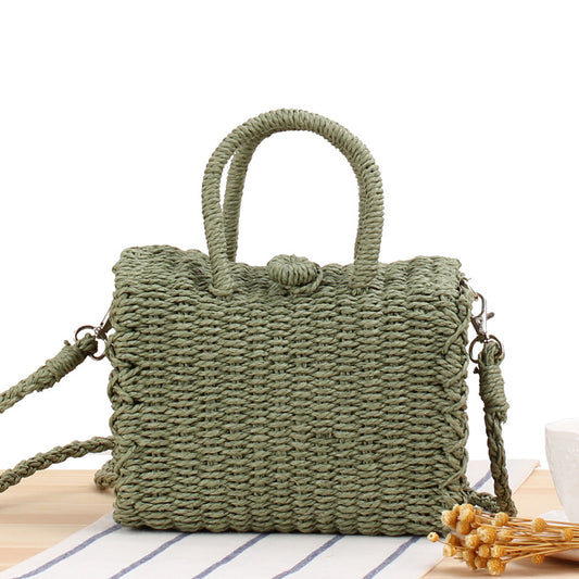 Sage green woven straw structured handbag with two top handles and a detachable strap.