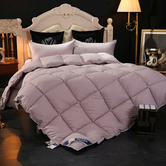 Plush quilted down comforter in soft mauve on a made bed with matching pillows.