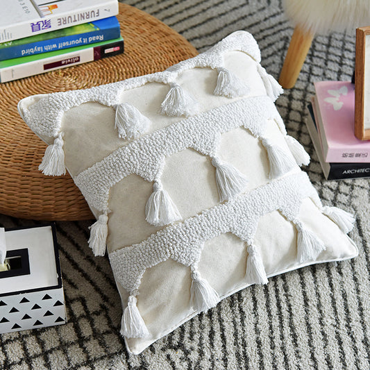 Throw pillow with tufted pattern and tassels on textured fabric