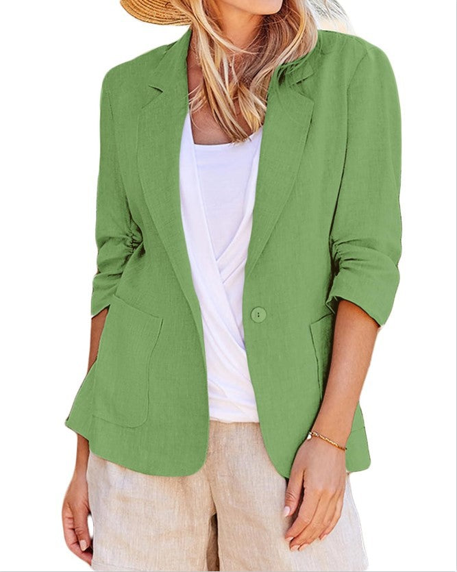 Woman wearing an open green single-breasted blazer over a white top and tan bottoms