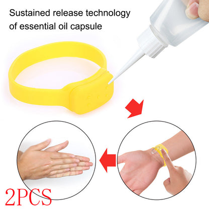 Yellow silicone refillable dispenser bracelet being filled from a squeeze bottle and worn on a wrist.