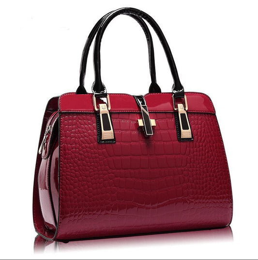 Women's red crocodile pattern patent leather tote handbag with black top handles and gold-tone hardware.