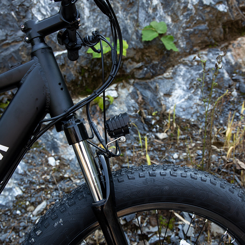 Matte black aluminum frame electric bike with wide knobby tires for all-terrain sports & outdoors mountain trail riding.