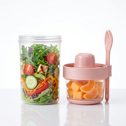 Open salad cup with fresh vegetables beside a small fruit cup with fork