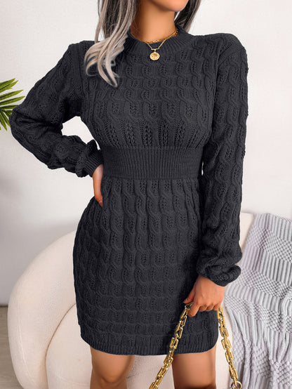 Black cable knit sweater dress with a fitted waist, long sleeves, and a ribbed texture for a day-to-night look.