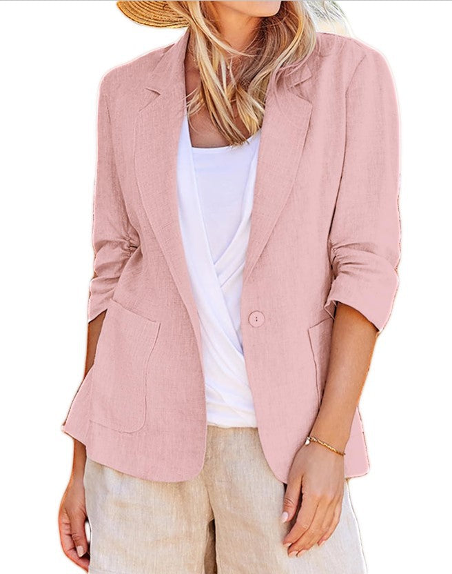 Woman wearing a pink open-front suit jacket with a single button and front patch pockets over a white top.