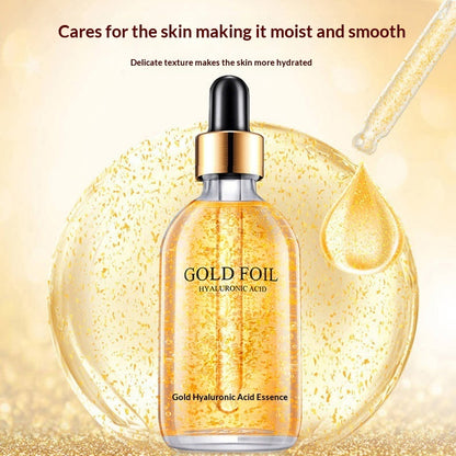 Gold foil hyaluronic acid facial serum bottle with dropper and droplet against a golden background.