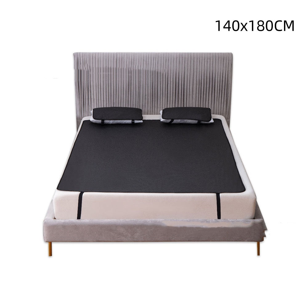 Black grounding mat spread across a bed with two matching pillows and dimensions 140x180cm