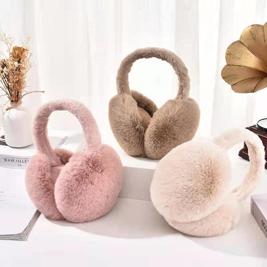 Three fluffy faux fur earmuffs in pink, tan, and cream displayed on a white surface.