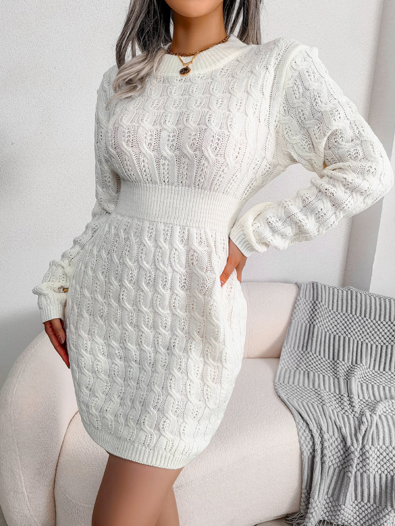 White cable knit sweater dress with a fitted waist, worn for cold weather style.