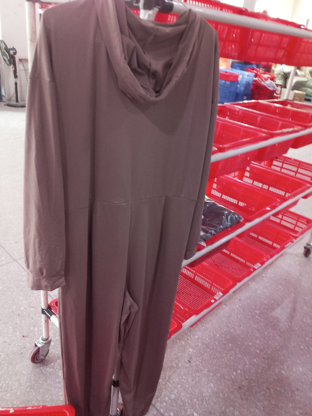 Back view of a brown hooded zip-up jumpsuit hanging on a rack.