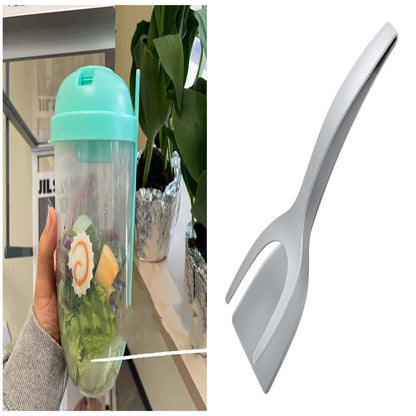 Clear salad cup with a light blue lid holding greens and dressing, alongside a grey spork.