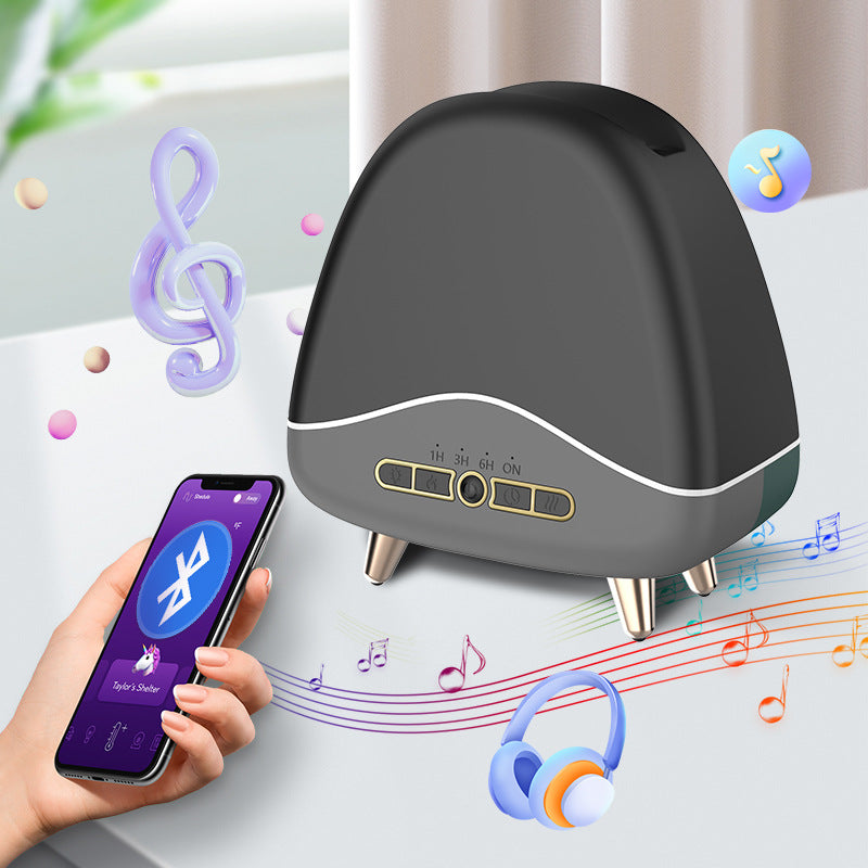 Black aroma diffuser on four legs next to a hand holding a smartphone showing a Bluetooth app.