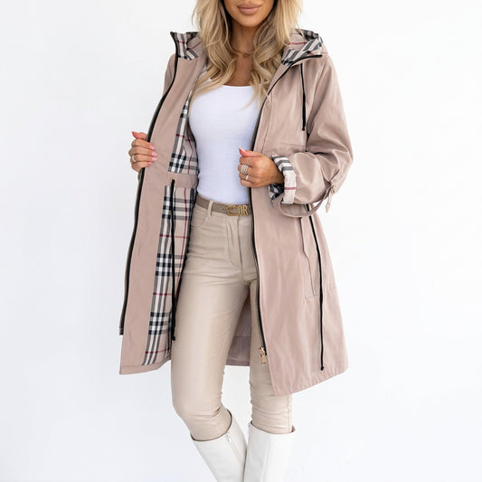 Woman wearing beige hooded jacket with plaid lining over white top and pants.