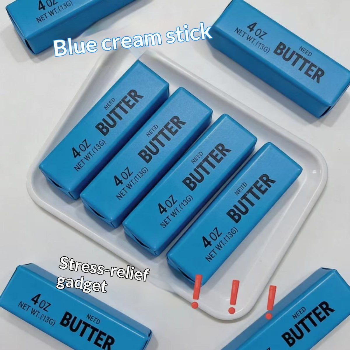 Blue butter stick stress relief toy on a white tray with text and exclamation mark graphics.