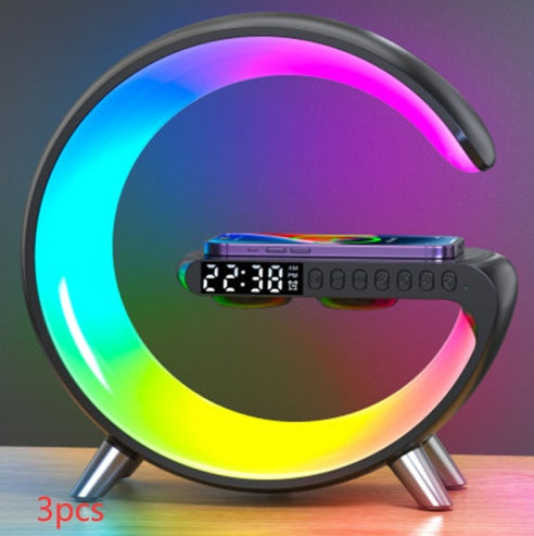 G-shaped black LED lamp with wireless charger and clock on a desk for nighttime charging and ambient lighting.