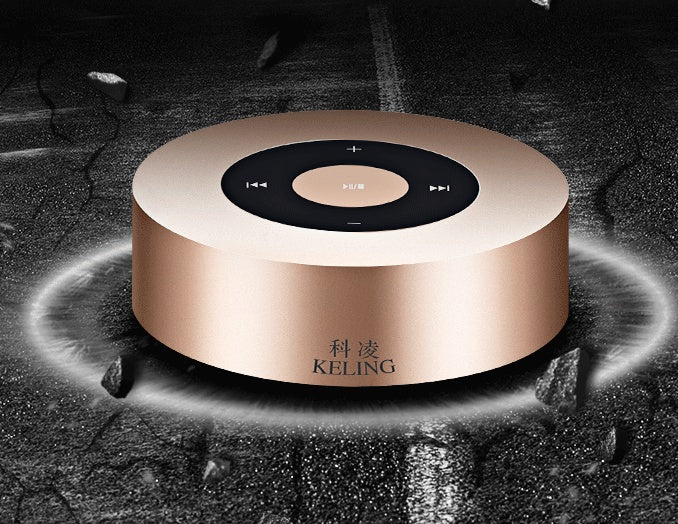Round rose gold wireless bluetooth speaker with black top control panel on dark textured background