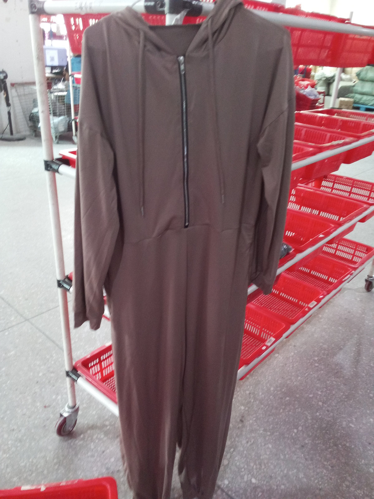 Close view of a hooded zip-up jumpsuit on a hanger showing the full-length zipper