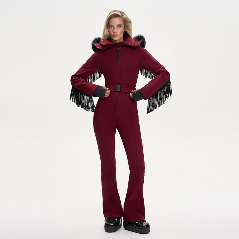 Model wearing a maroon ski jumpsuit with fringe on sleeves, a fur-trimmed hood, and a waist belt.