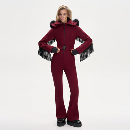 Model wearing a maroon ski jumpsuit with fringe on sleeves, a fur-trimmed hood, and a waist belt.