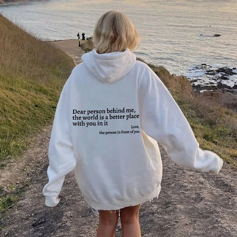 White oversized hoodie with black inspirational letter print, worn for casual outings.