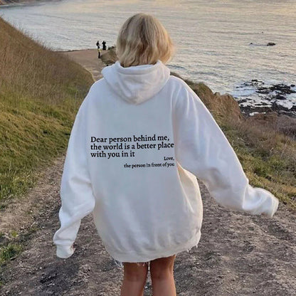 White oversized hoodie with black inspirational letter print, worn for casual outings.