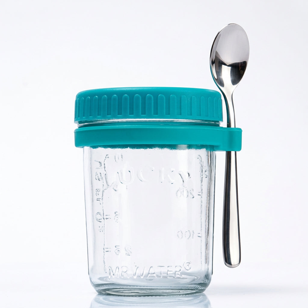 Clear glass overnight oats jar with teal lid and a spoon held in a silicone band on the side