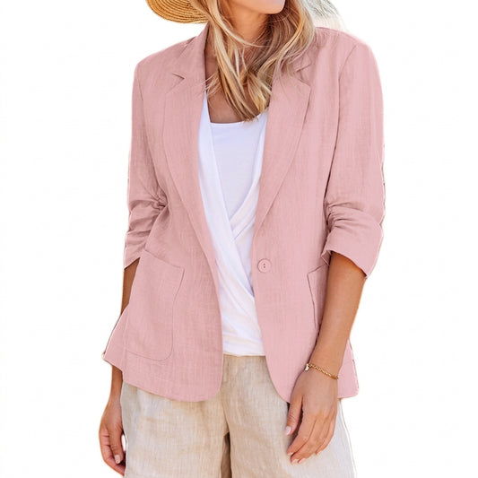 A woman wearing a pink open-front blazer with notched lapels, rolled-up sleeves, and front pockets over a white top.