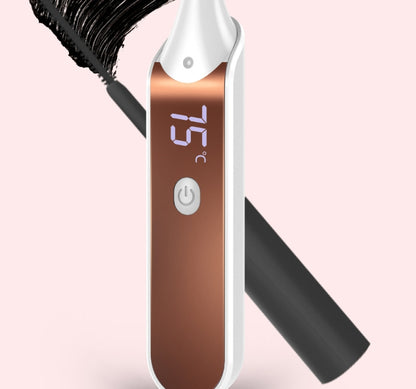 Heated eyelash curler with digital temperature display beside a mascara wand