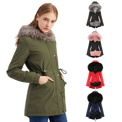 Woman wearing an olive green hooded parka coat with faux fur trim, drawstring waist, and pockets.