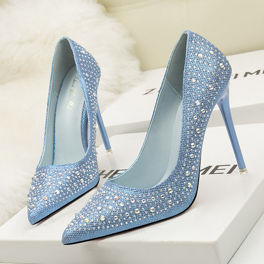 Blue glitter stiletto pumps with pointed toes and rhinestone embellishments, shown on boxes.
