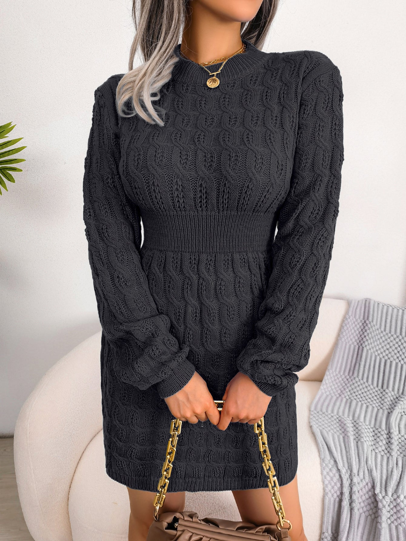 Black cable knit sweater dress with a fitted, waist-defining silhouette for cozy winter wear.