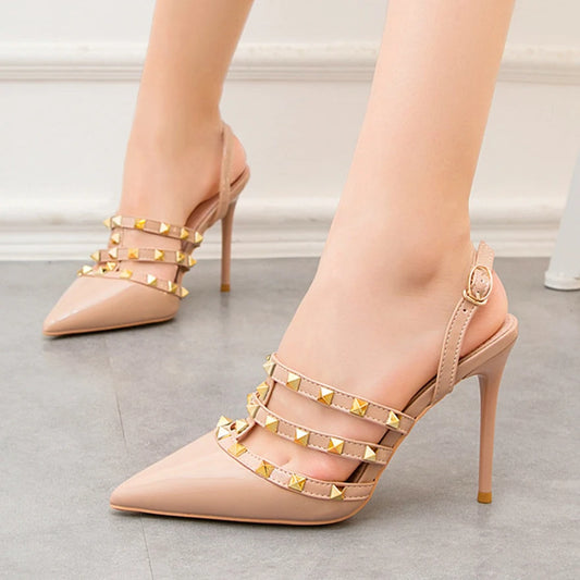 Beige pointed pumps with gold rivet straps and an adjustable ankle, strappy dress shoes for office attire.