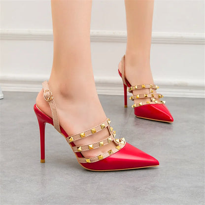 Red patent leather pumps with gold rivet straps and back ankle strap for office wear.