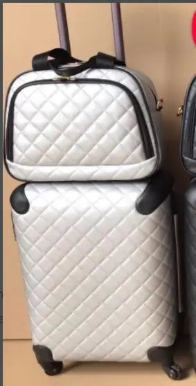 Silver quilted leather luggage set including a spinner trolley suitcase with wheels and a matching vanity bag.