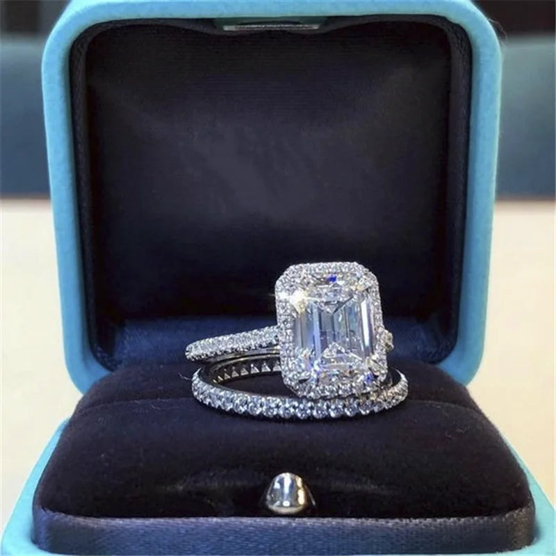 Two-piece silver ring set with large emerald-cut cubic zirconia and pave rhinestones in a blue box.