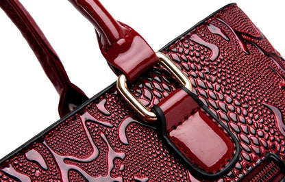 Deep red, faux leather shoulder tote with snake-embossed pattern, gold metal hardware, and zip closure for daily use.