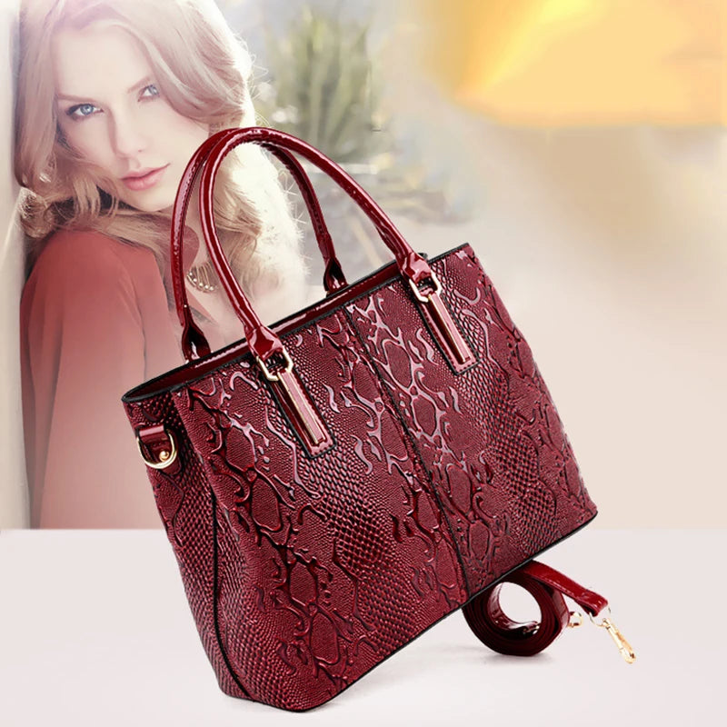 Shiny deep red snake-print structured bag with dual handles and an adjustable strap for daily commute.