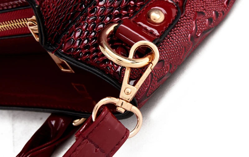 Deep red faux leather crossbody bag with snake-skin texture, gold hardware, and an adjustable strap for daily carry.