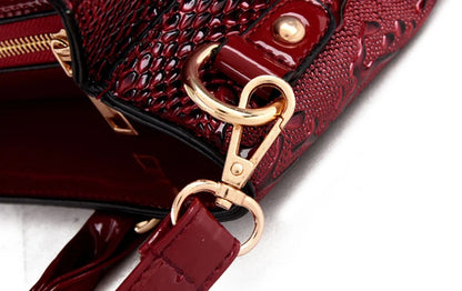 Deep red faux leather crossbody bag with snake-skin texture, gold hardware, and an adjustable strap for daily carry.