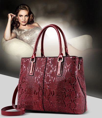Red faux leather structured shoulder tote with snakeskin texture, zip closure, and adjustable strap for daily carry.
